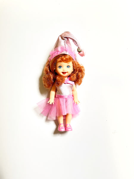 Vintage 1999 Mattel Barbie Kelly Club doll dressed as the Lullaby Munchkin from The Wizard of Oz. The miniature doll features curly red hair, a pink and silver tutu outfit, a tall pointed conical hat, and pink shoes, displayed against a clean white background
