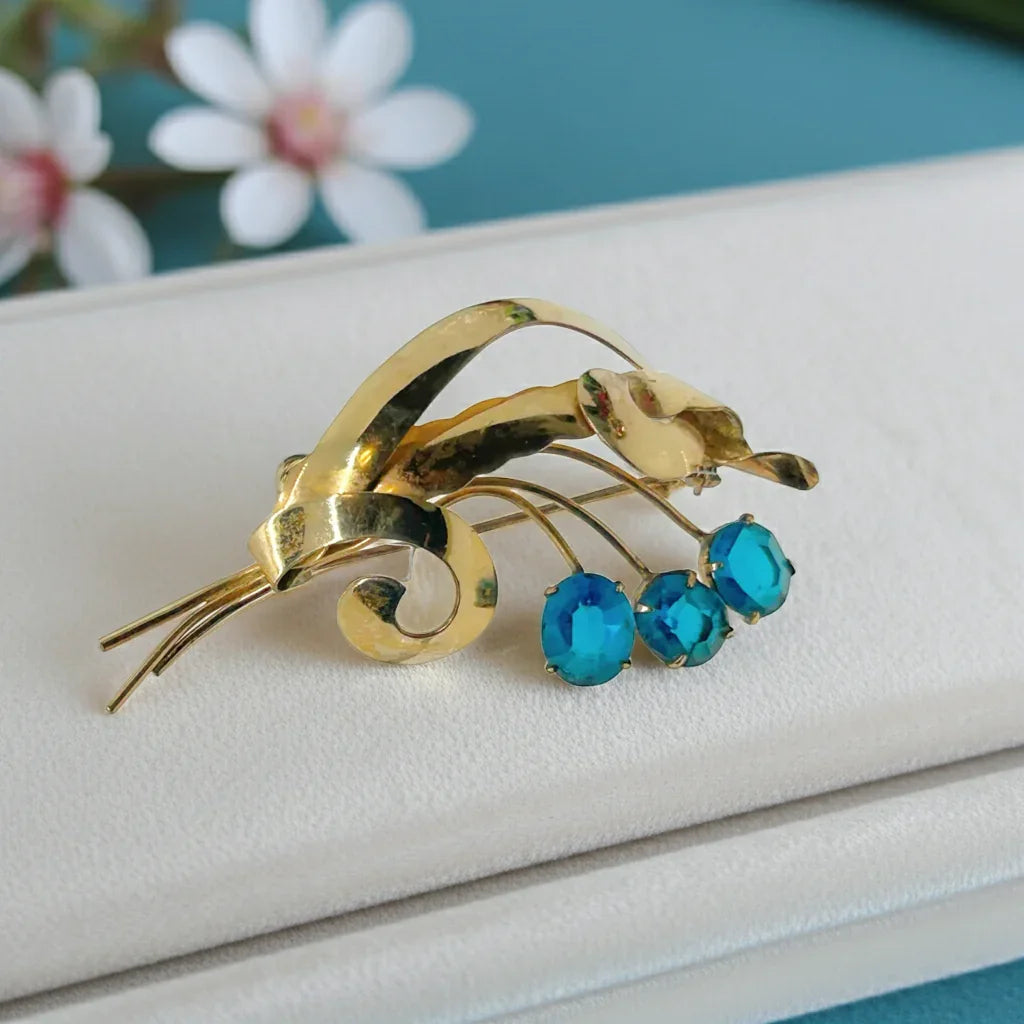 Perfect for vintage lovers: our Striking Gold Filled Oval Teal Blue Vintage Flower Spray Brooch provides timeless charm with bold teal stones. Shop today!