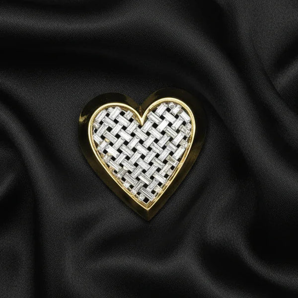 This is a bold and striking brooch by famed designer Nolan Miller. His pieces are consistently high quality and this heart shaped brooch is an excellent example of that, with it's smooth gold tone border and its perfectly set, clear and bright baguettes forming a woven-look appearance. 