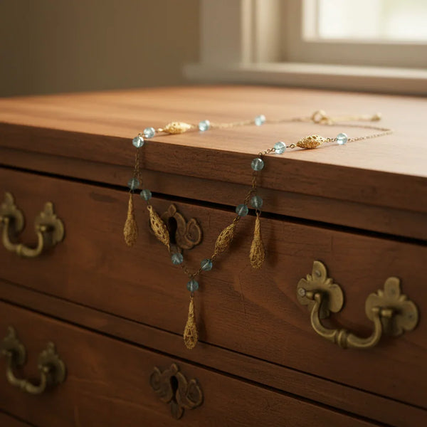 This is a beautiful antique drop necklace, made of golden filigree beads interspersed with clear blue glass accent beads, and punctuated by flat abstract filigree drops. It measures approximately 32" inches long, and the filigree beads each measure about 1”