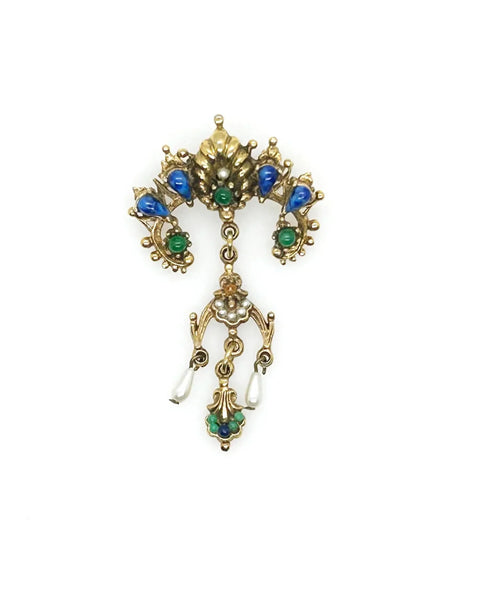 A splendid specimen of Renaissance Revival style, this Vintage ART Brooch showcases the maker's hallmark artistry through its exquisite detailing. Adorned with faux lapis, jade, turquoise, and pearl accents set within ornate gold-tone metalwork, it presents a harmonious marriage of color and design.