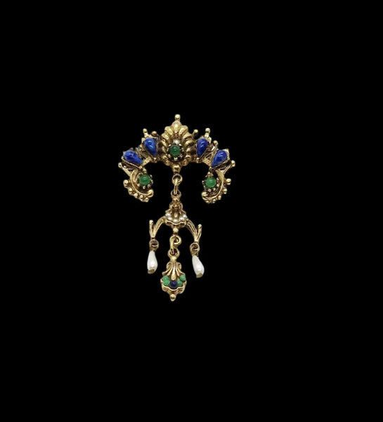 A splendid specimen of Renaissance Revival style, this Vintage ART Brooch showcases the maker's hallmark artistry through its exquisite detailing. Adorned with faux lapis, jade, turquoise, and pearl accents set within ornate gold-tone metalwork, it presents a harmonious marriage of color and design.