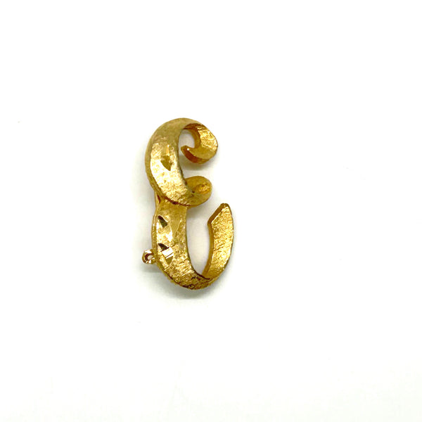 A small, vintage gold-tone initial "E" cursive monogram brooch pin, featuring a dual-textured finish with brushed matte styling and diamond-cut highlights on a plain white background