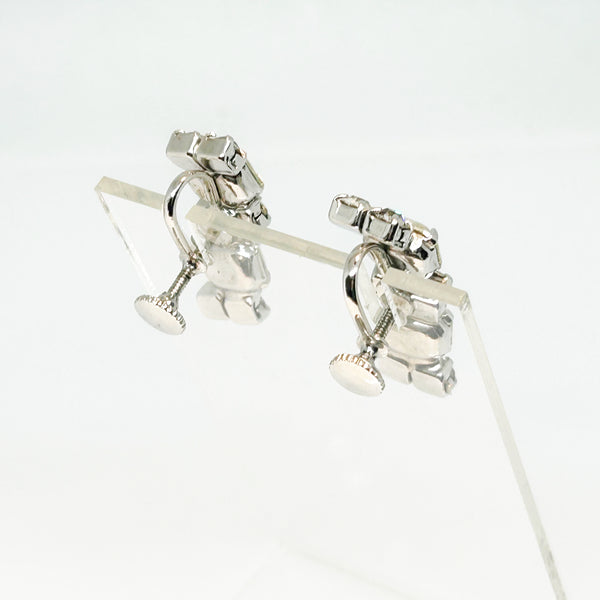  The earrings feature a unique stacked, half-hoop design. Emerald-cut stones elegantly alternate with two small, round stones, creating a captivating contrast. 