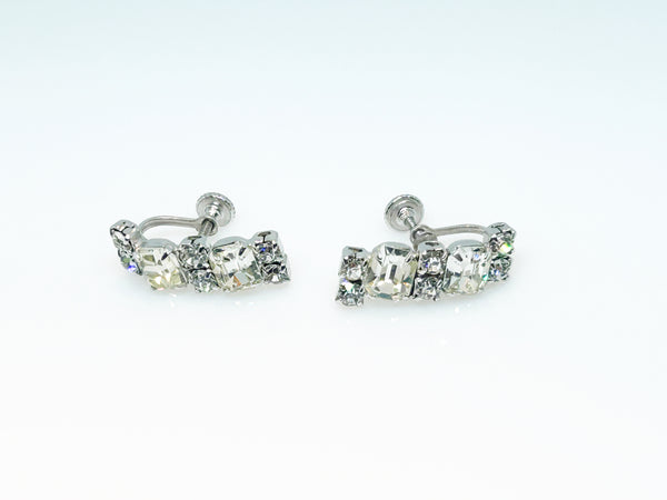  The earrings feature a unique stacked, half-hoop design. Emerald-cut stones elegantly alternate with two small, round stones, creating a captivating contrast. 