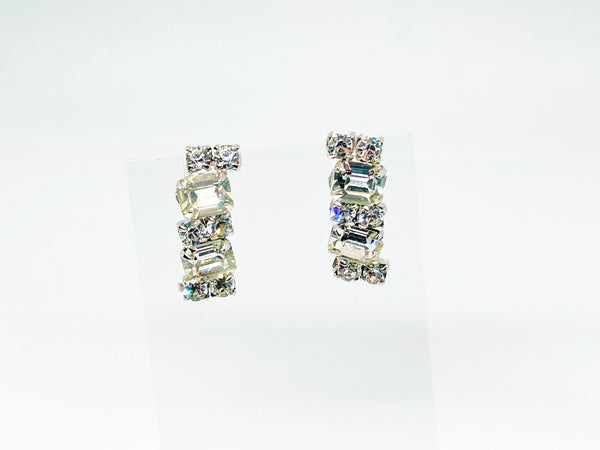  The earrings feature a unique stacked, half-hoop design. Emerald-cut stones elegantly alternate with two small, round stones, creating a captivating contrast. 