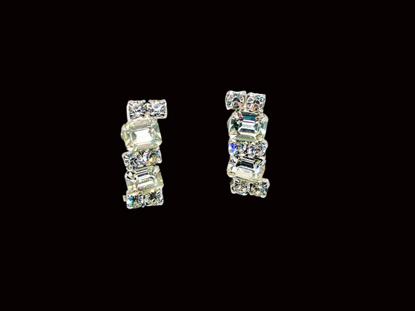  The earrings feature a unique stacked, half-hoop design. Emerald-cut stones elegantly alternate with two small, round stones, creating a captivating contrast. 