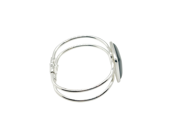 This striking vintage bracelet showcases a bold black square onyx stone set in polished silver. The architectural design features dual silver bands converging at the center stone with a hinged hook-bangle closure for easy wear. 