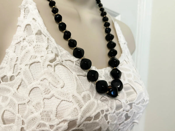 This unusual and striking vintage Avon necklace is made of graduated, asymmetrical black beads with gold-tone bead separators. It dates to the mid-1980's, is signed Avon in block letters on the spring clasp, and measures 24" long.