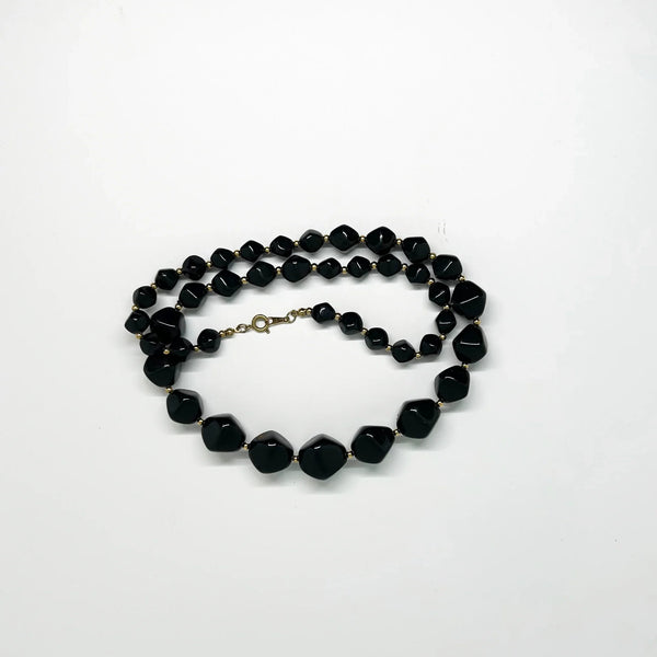 This unusual and striking vintage Avon necklace is made of graduated, asymmetrical black beads with gold-tone bead separators. It dates to the mid-1980's, is signed Avon in block letters on the spring clasp, and measures 24" long.
