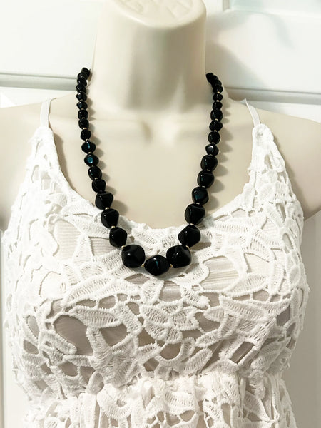 This unusual and striking vintage Avon necklace is made of graduated, asymmetrical black beads with gold-tone bead separators. It dates to the mid-1980's, is signed Avon in block letters on the spring clasp, and measures 24" long.
