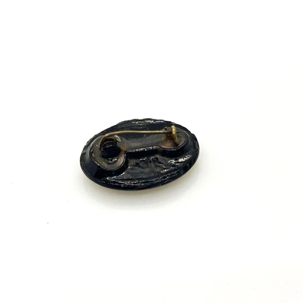 Discover this exquisite antique Victorian black glass brooch, a poignant piece of mourning jewelry originating from the mid-to-late 19th century. This captivating oval brooch boasts a delicately beaded border, framing a mesmerizing central design that evokes either a floral motif or a radiant starburst pattern. 