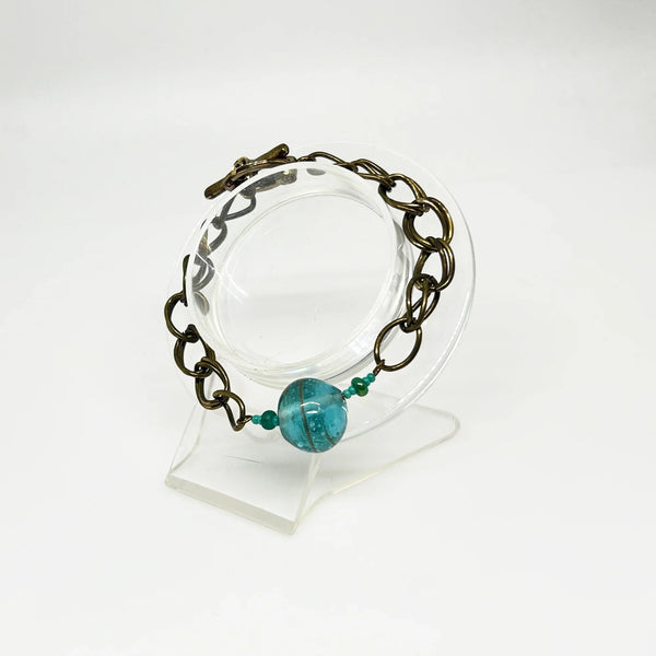 This captivating vintage bracelet boasts two rows of links on either side of a stunning blue glass marble with shimmering gold stripes. It is 7 1/2" in length and features a charming toggle clasp