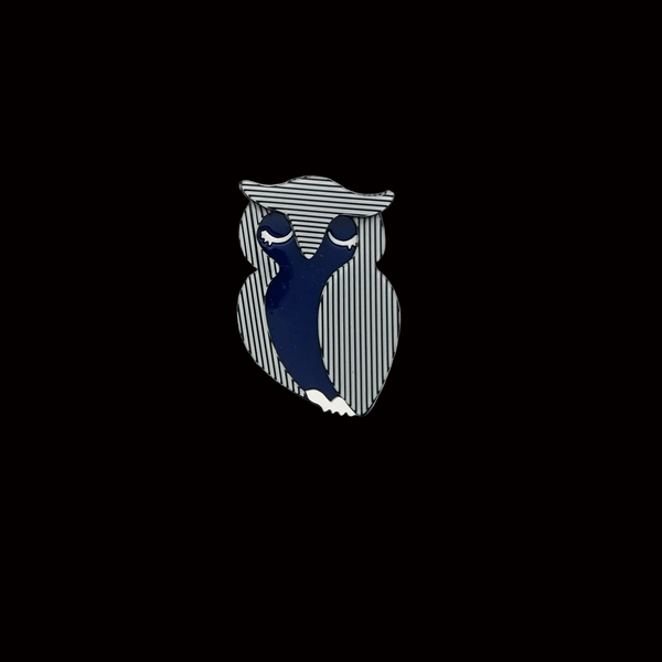 Lightweight acrylic resin brooch shaped like a stylized owl. Features a bold optical art design with vertical black and white stripes and a solid royal blue body. Secure metal pin back attached.