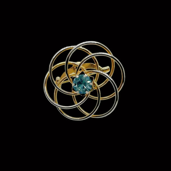 Step back in time with this charming 1960s brooch that proves vintage doesn't mean expensive. Delicate gold swirls dance around a brilliant light blue rhinestone, creating just the right amount of sparkle without trying too hard. 