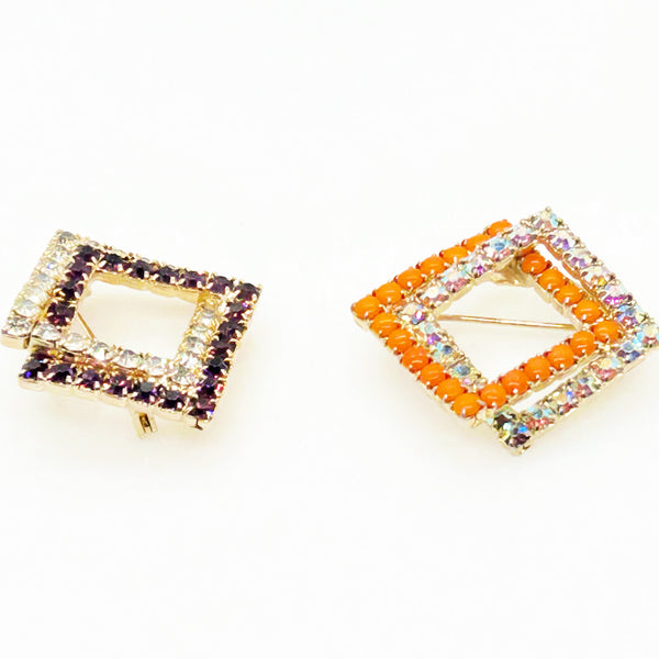 Set of two vintage 3D interlocking square brooches. One features purple and clear prong-set rhinestones on a silver-tone frame. The other features opaque orange and sparkling gold AB crystals on a gold-tone geometric frame