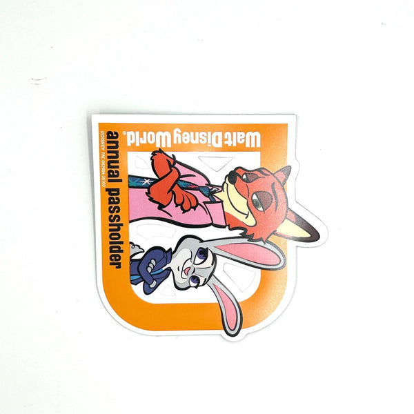 Celebrate your Disney magic with this cheerful 2026 Walt Disney World Annual Passholder Magnet featuring Nick Wilde and Judy Hopps from Zootopia! Shaped like a bold capital 'D', this exclusive winter edition magnet showcases the beloved fox-and-bunny duo in vibrant detail.