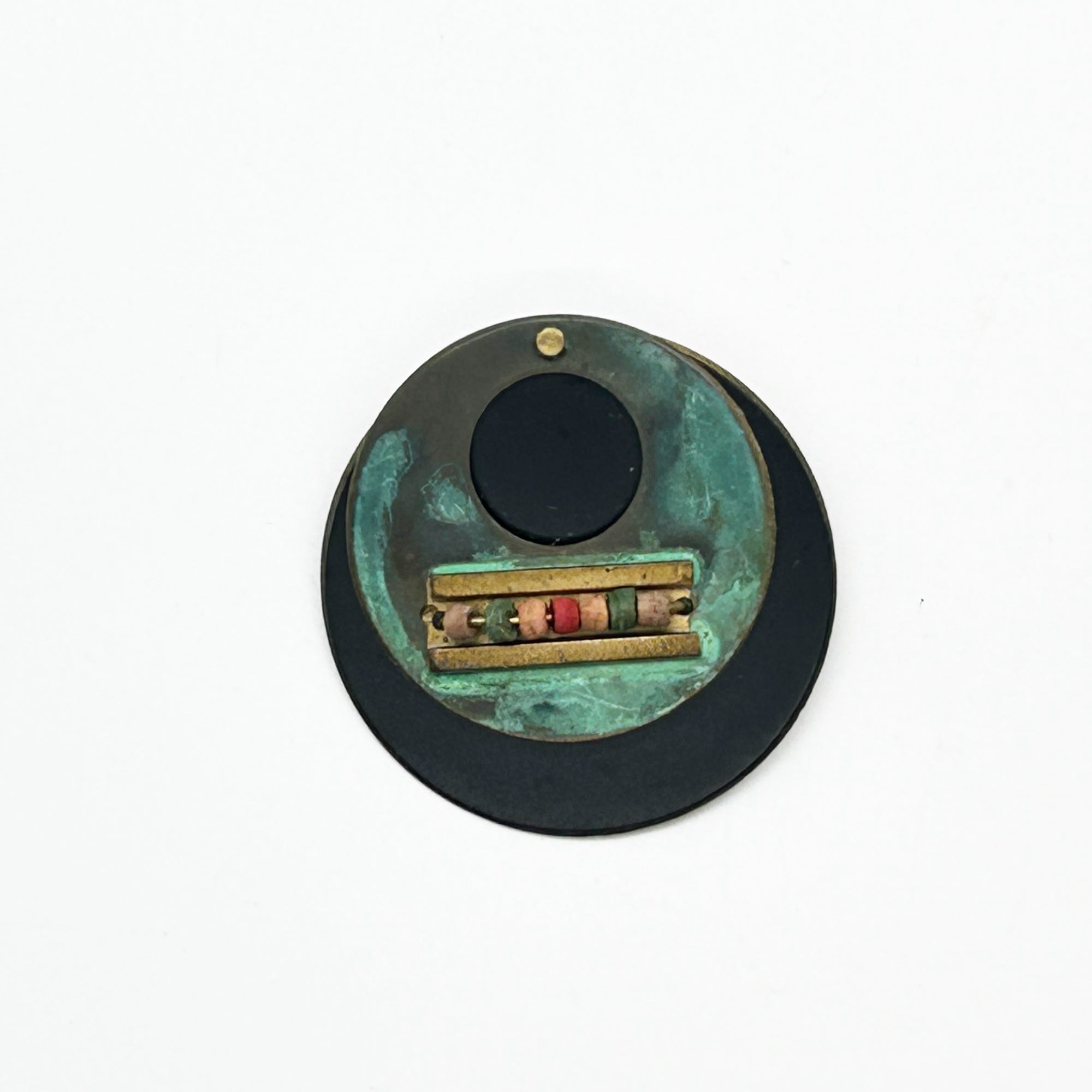 Intriguing modernist brooch with layered circular components, including a dark, possibly rubber or ebonized material, and a verdigris-patinated or painted metal plate.