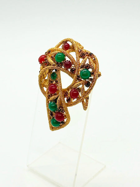 1960s vintage Capri openwork curl brooch featuring textured gold-tone metal set with green faux jade and red carnelian glass cabochons