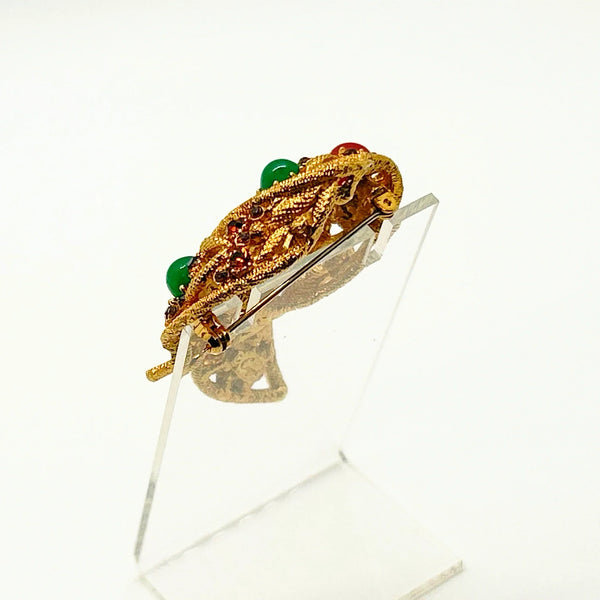 1960s vintage Capri openwork curl brooch featuring textured gold-tone metal set with green faux jade and red carnelian glass cabochons