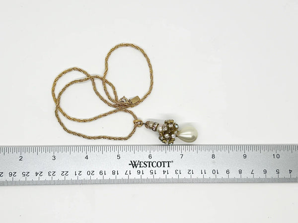 On a rich gold tone rope chain, which is matched by the bail,&nbsp; is suspended a pendant with first, a small round luminous round pearl, followed by a glittering rhinestone roundel, followed by a slightly larger round pearl.