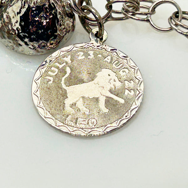 Silver charm bracelet with various charms on a white background
