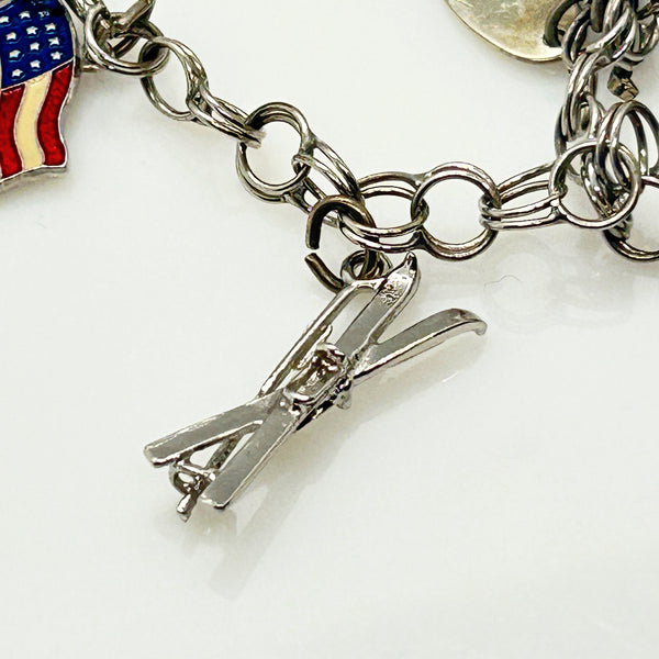Silver charm bracelet with various charms on a white background