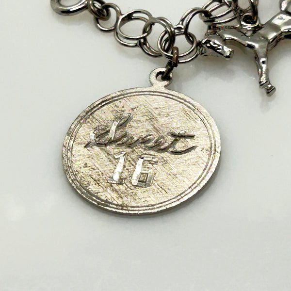 Silver charm bracelet with various charms on a white background