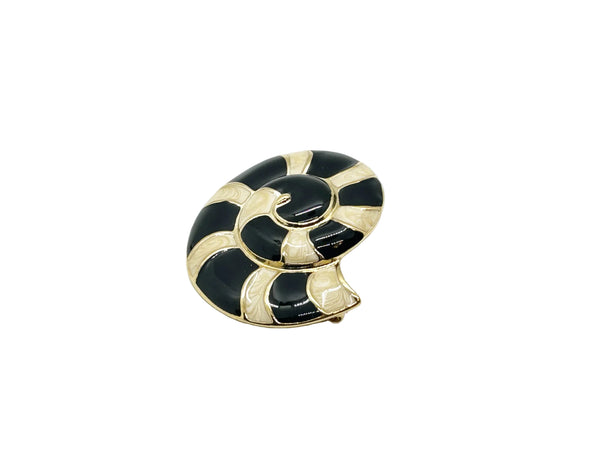 This stunning Trifari brooch captures the elegance of Art Deco design with its spiral seashell silhouette. Crafted in gold-tone metal, it features striking black enamel paired with creamy golden-sand enamel in a sophisticated moire finish.