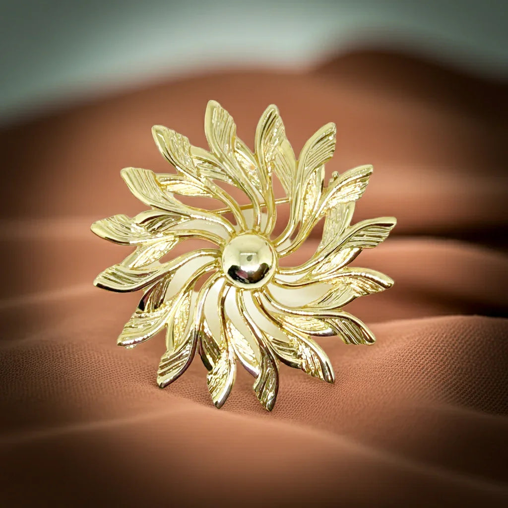 Celebrate timeless elegance with this Sarah Coventry Gold Tone Sunburst Flower Brooch. Featuring a beautifully textured gold-tone design, this vintage piece captures the radiant energy of a blossoming flower or a glowing sunburst.