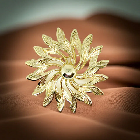Celebrate timeless elegance with this Sarah Coventry Gold Tone Sunburst Flower Brooch. Featuring a beautifully textured gold-tone design, this vintage piece captures the radiant energy of a blossoming flower or a glowing sunburst.