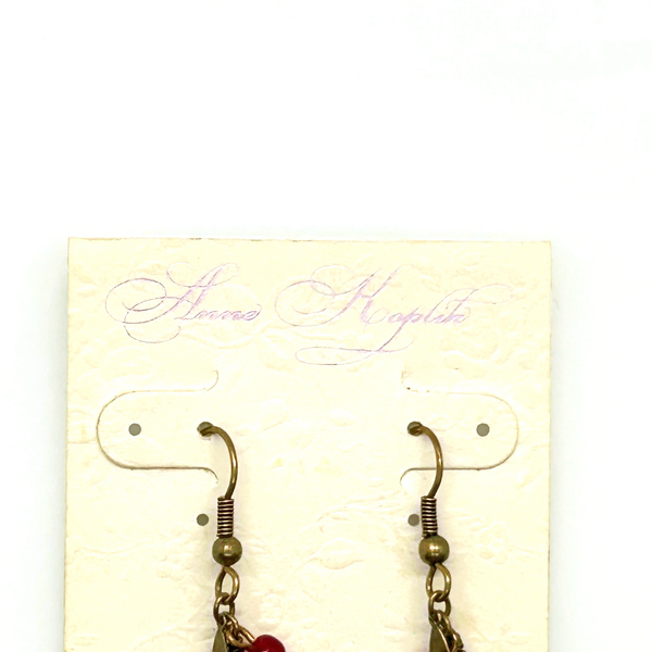 Vintage Cookie Lee nautical charm dangle earrings in antiqued brass with anchor, sailboat, fish, and blue star charms on a cream card.