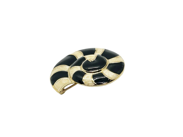 This stunning Trifari brooch captures the elegance of Art Deco design with its spiral seashell silhouette. Crafted in gold-tone metal, it features striking black enamel paired with creamy golden-sand enamel in a sophisticated moire finish.
