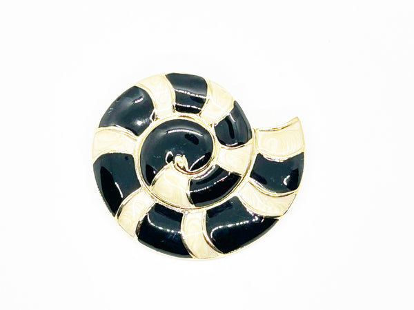 This stunning Trifari brooch captures the elegance of Art Deco design with its spiral seashell silhouette. Crafted in gold-tone metal, it features striking black enamel paired with creamy golden-sand enamel in a sophisticated moire finish.