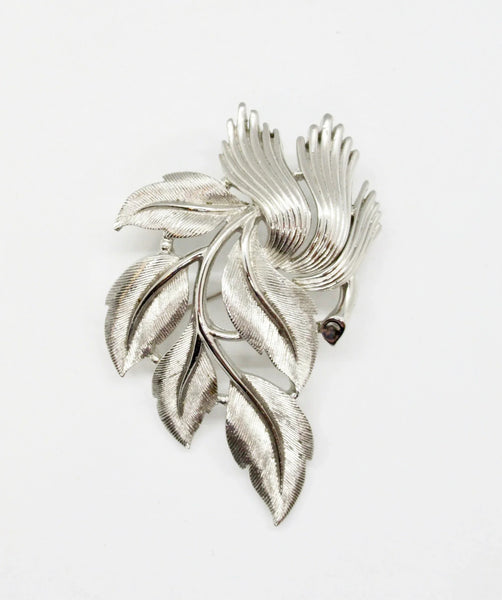 An exquisite piece of vintage jewelry, the Crown Trifari Brushed Silver tone Leaf Brooch boasts eight beautifully crafted leaves, with five showcasing brushed silver tone metal and three displaying a stylized abstract design
