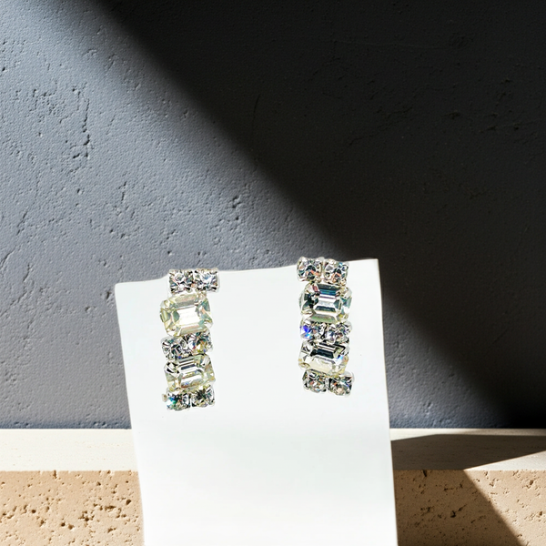 The earrings feature a unique stacked, half-hoop design. Emerald-cut stones elegantly alternate with two small, round stones, creating a captivating contrast.