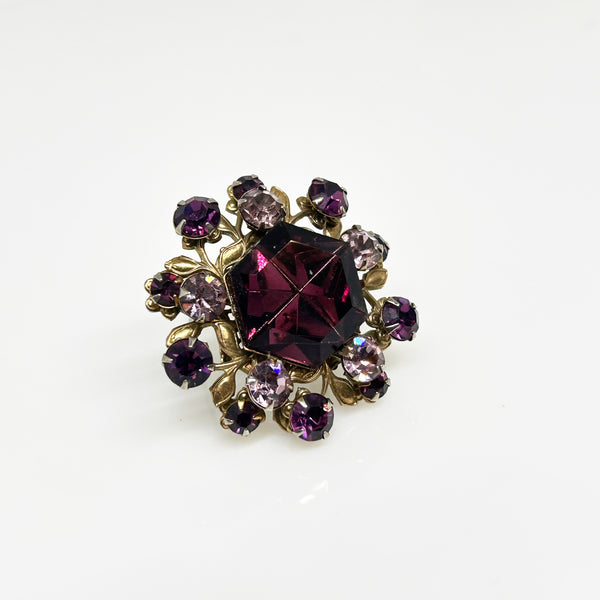 This dazzling brooch features a large octagonal purple stone at its center, surrounded by sparkling lavender and purple round stones. Its two-tiered design highlights the bezel-set centerpiece, making it truly eye-catching. With intricate details that showcase exceptional Czech craftsmanship,