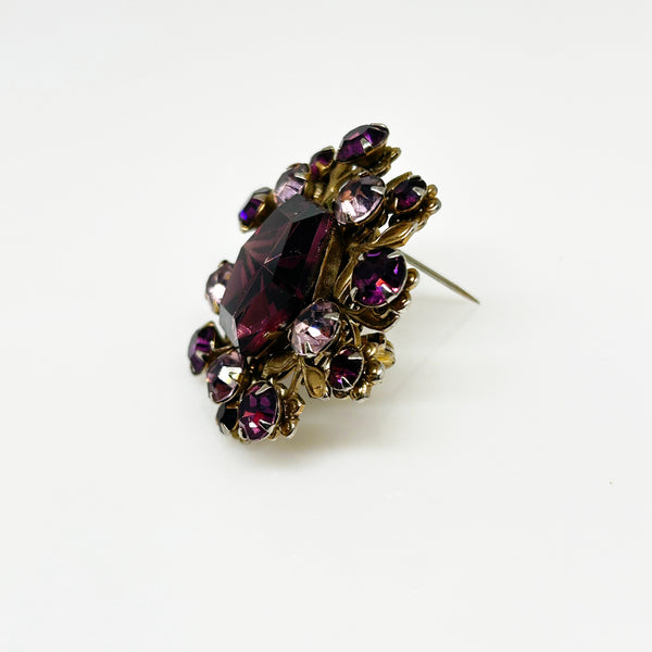 This dazzling brooch features a large octagonal purple stone at its center, surrounded by sparkling lavender and purple round stones. Its two-tiered design highlights the bezel-set centerpiece, making it truly eye-catching. With intricate details that showcase exceptional Czech craftsmanship,