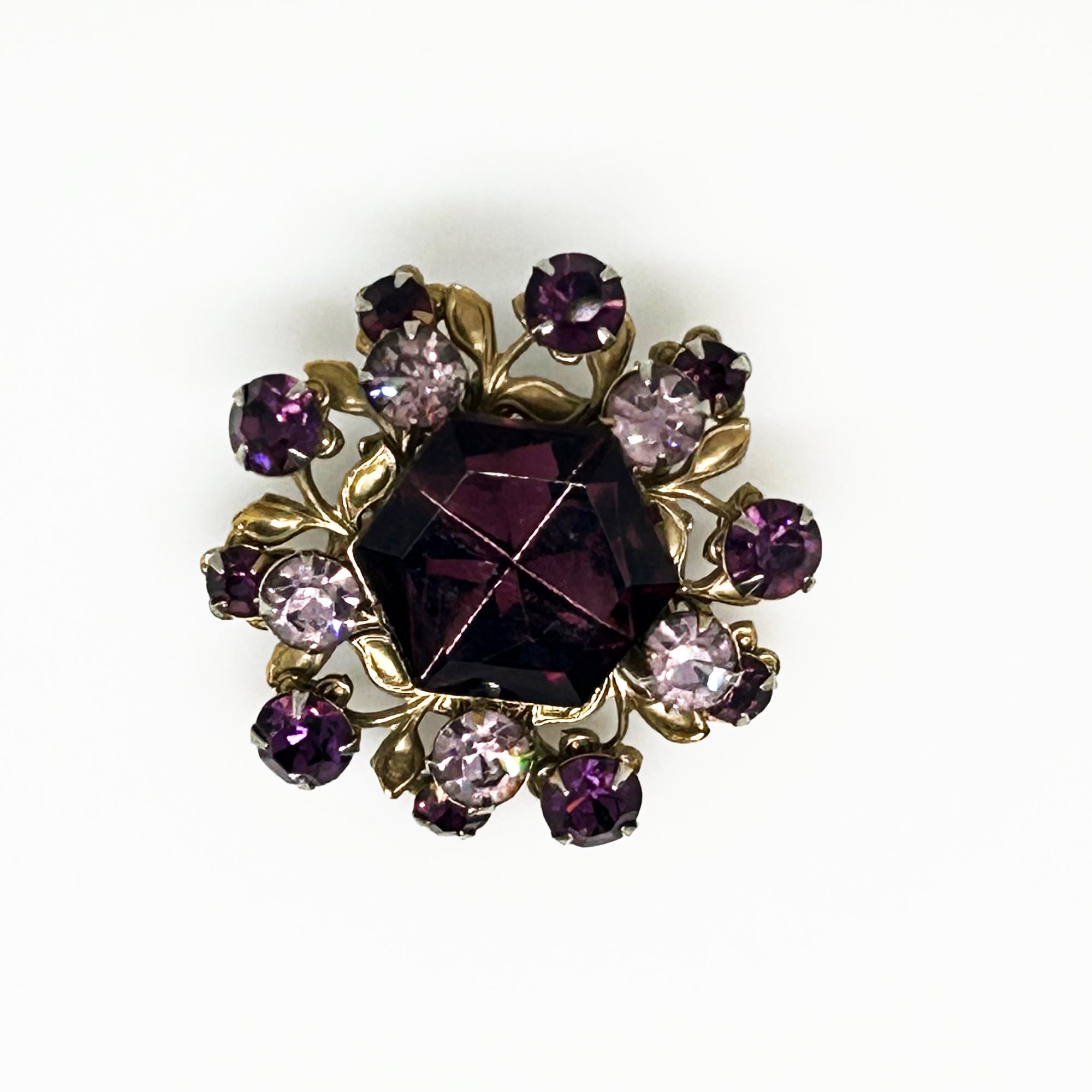 This dazzling brooch features a large octagonal purple stone at its center, surrounded by sparkling lavender and purple round stones. Its two-tiered design highlights the bezel-set centerpiece, making it truly eye-catching. With intricate details that showcase exceptional Czech craftsmanship,