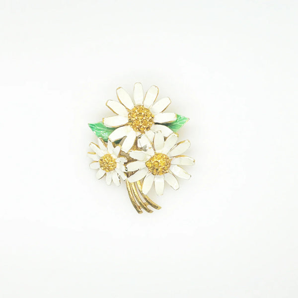 This is a cheerful vintage daisy brooch with enameled petals and a domed golden rhinestone center. It measures 2" long and is in good condition.