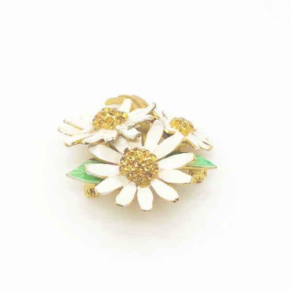 This is a cheerful vintage daisy brooch with enameled petals and a domed golden rhinestone center. It measures 2" long and is in good condition.