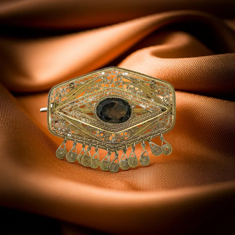 Vintage Israel Filigree Brooch/pendant with Tassels and Smokey Quartz center Stone.It has a geometric shape with tiny filigree drops at the bottom, and a large, faceted oval stone is the centerpiece.&nbsp; The metal is extremely intricate and detailed, both front and back.&nbsp; It measures approximately 2.75 Inches wide x 2.25" Tall. 