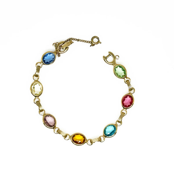 This lovely vintage bracelet is made by Emmons. It’s crafted with seven faceted oval clear bezel set stones. The colors of these stones are pale green, pink, aqua blue, citrine, light purple, pale yellow, and medium blue.