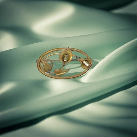 This exquisite Art Nouveau floral brooch showcases the timeless beauty of two delicate calla lilies in full bloom. The lilies are accented with sparkling baguette rhinestones. Skillfully designed in an elegant oval shape and measuring one and a half inches across, this is a rare find in mint condition.