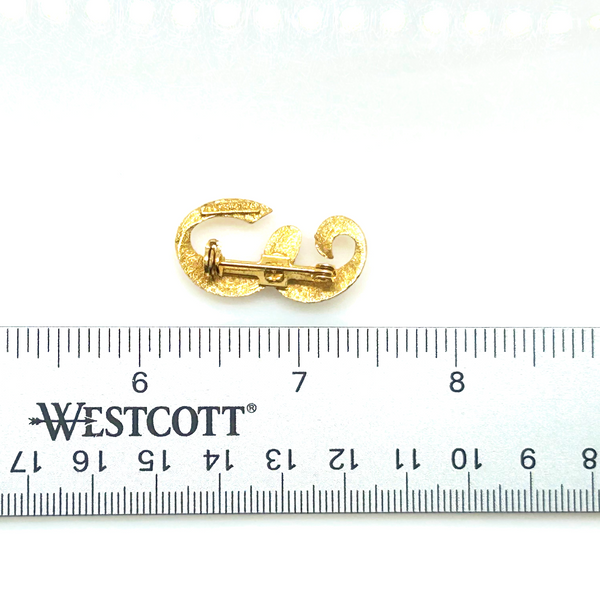 A small, vintage gold-tone initial "E" cursive monogram brooch pin, featuring a dual-textured finish with brushed matte styling and diamond-cut highlights on a plain white background