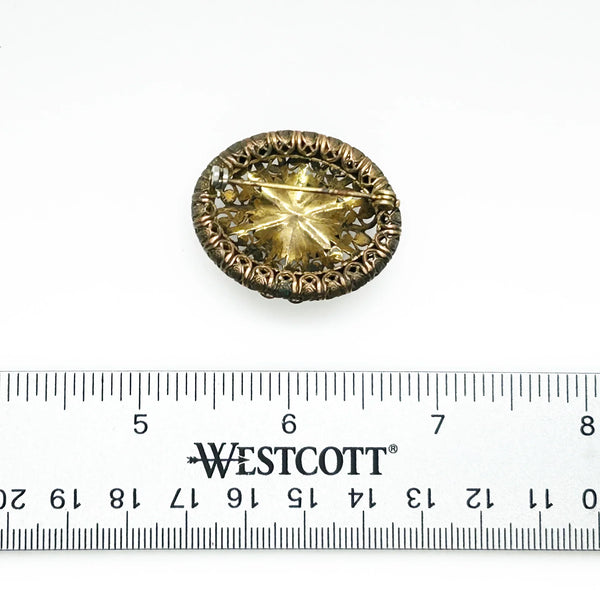 This lovely vintage brooch has a beautiful golden faceted oval stone surrounded by layers of elaborately detailed filigree. The workmanship is outstanding. The stone is prong set and secure; it's a very wearable brooch. It measures 1.5" across and is in very good condition.