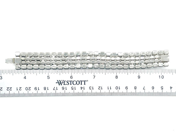 This vintage rhinestone bracelet provides an elegant touch to any ensemble. Featuring four rows of meticulously prong-set rhinestones, it measures approximately 7 inches in length and 0.75 inches in width. 