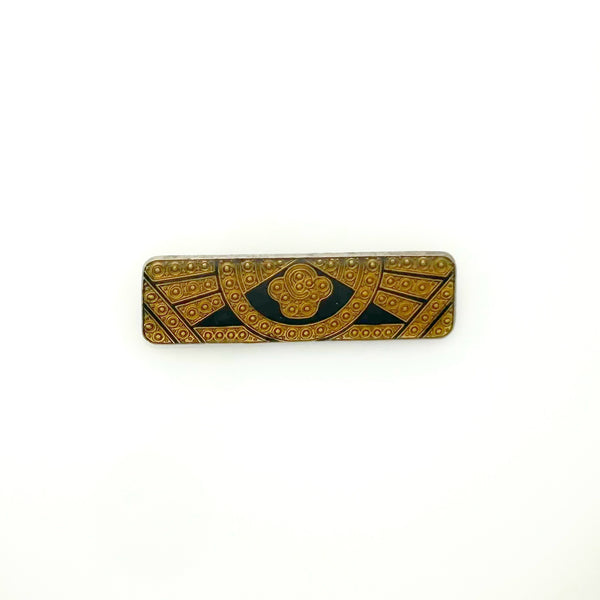 A vintage rectangular Art Deco revival bar brooch in the Pierre Bex style, featuring textured gold-tone metal sunburst rays, dark enamel details, and a central floral cloud medallion against a solid white background