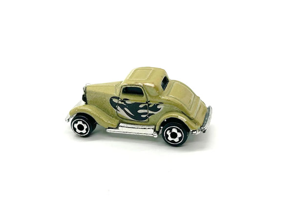 A miniature toy hot rod car in a metallic olive green finish with black and white flame decals on the side, set against a plain white background.