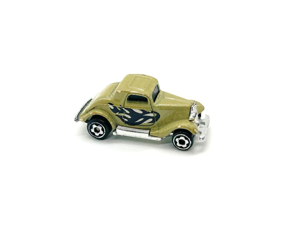 A miniature die-cast toy car resembling a vintage 1930s coupe, finished in olive green with black and white flame decals on the side, set against a plain white background.